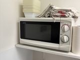 un micro-ondes posé sur une étagère dans un coin de la pièce