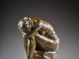 a bronze statue of a man sitting on a rock