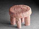 une image représentant un tabouret rose posé sur un sol en béton