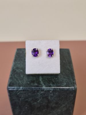 une paire de boucles d'oreilles en améthorate posées sur un bloc de marbre
