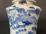 a blue and white vase with a handle on a table