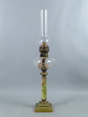 une lampe à huile ancienne avec un socle vert et un globe en verre transparent