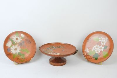 three small plates with flowers painted on them sit on a stand