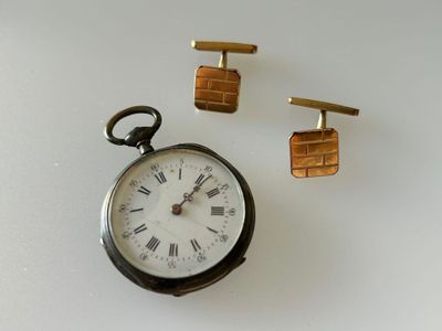 a pocket watch and cufflinks sitting on a table
