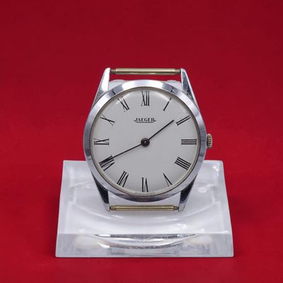 une image représentant une montre blanche posée sur un socle transparent, sur fond rouge