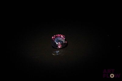 un diamant violet dans l'obscurité, dont le reflet se dessine sur le sol