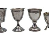 three silver goblets and spoons sitting next to each other on a white surface