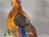 a small ceramic rooster on a plate with a spoon