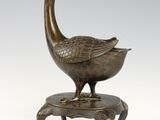 bronze sculpture of a bird on a stand on a white background