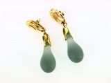 paire de boucles d'oreilles pendantes en verre vert rehaussées de touches dorées sur fond blanc