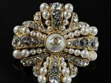 a close up of a pearl and diamond broochle on a black surface