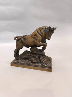 statue en bronze représentant un taureau posé sur un rocher, sur un fond blanc