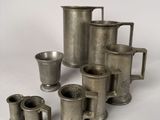 a lot of silver cups and mugs sitting on a table
