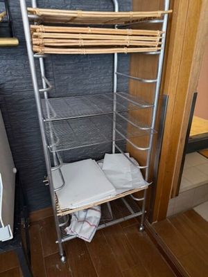 une étagère métallique sur laquelle sont posées des serviettes, dans un coin de la pièce