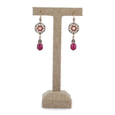 une paire de boucles d'oreilles avec des perles roses sur un support