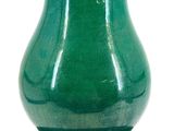 a green vase sitting on top of a white table