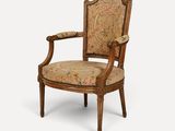 an old chair with a floral upholstered back and arms