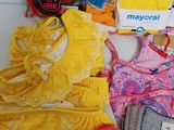 a lot of baby clothes and a purse on a table
