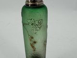a green glass bottle with a silver lid on a white surface