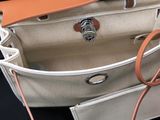beige and white canvas bag with leather handles on a black surface