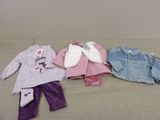 three children ' s clothes are lined up on a bed