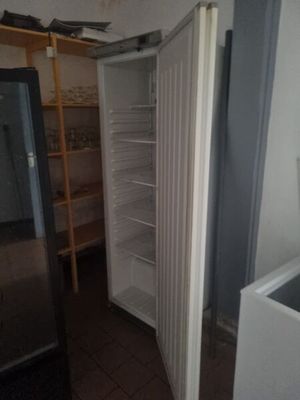 a refrigerator in the corner of a room with a door open