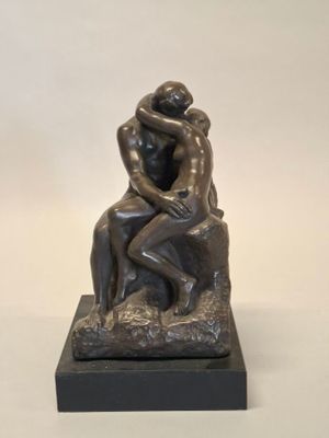 une statue représentant un couple assis sur un rocher, enlacés