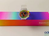 swatch watch in a box on a white surface with a rainbow background
