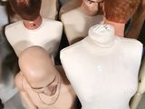 Plusieurs mannequins sont alignés dans une pièce aux murs blancs