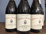 three bottles of wine sitting on top of a wooden table