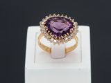 gros plan d'une bague avec une pierre violette entourée de diamants