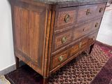 a wooden chest of drawers with marble top on a rug