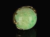a close up of a green stone ring on a black surface