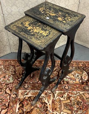 une paire de tables d'appoint anciennes, noires et dorées, posées sur un tapis