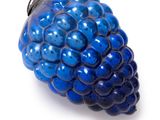 a blue glass ornament with a bunch of blue berries on it
