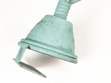 a green metal bell hanging from the side of a white wall