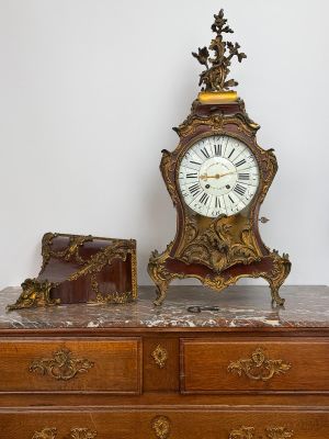 a clock sitting on top of a dresser next to a suitcase