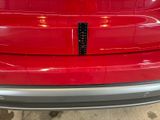 the rear end of a red car with a sticker on it ' s bumper