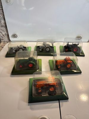 six camions miniatures exposés sur une table blanche