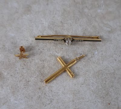 une petite croix en or et une autre petite croix en or par terre