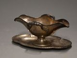 une assiette en argent sur laquelle repose une soucoupe en argent