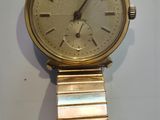 une montre en or sur une surface blanche avec un fond blanc