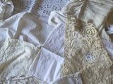 beaucoup de vêtements blancs posés sur un lit, à côté d'une table en bois