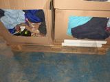 two cardboard boxes with clothes on them sitting on the floor