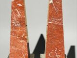 pair of red marble obelisks with black bases on a white background