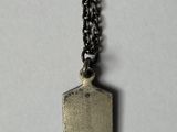 a close up of a metal tag on a chain on a white surface