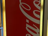 a coca cola machine sitting on the floor in a room