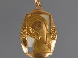 une image représentant un pendentif en or sur lequel figure une femme tenant un couteau