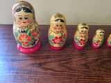 five matry dolls lined up on a wooden table