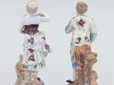 pair of porcelain figurines of a woman and a man with a dog